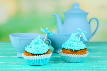 Tasty cup cakes with cream on blue wooden table