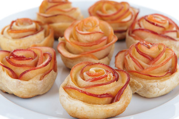 Tasty puff pastry with apple shaped roses on plate close-up