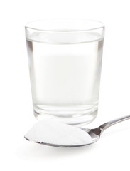Spoon of baking soda over glass of water, isolated on white