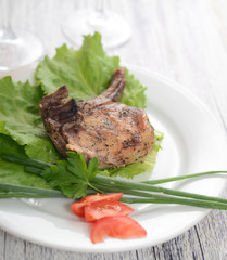 pork steak on lettuce with tomatoes and onions