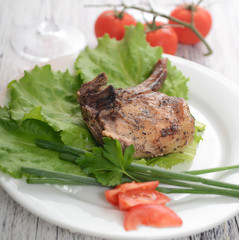 pork steak on lettuce with tomatoes and onions