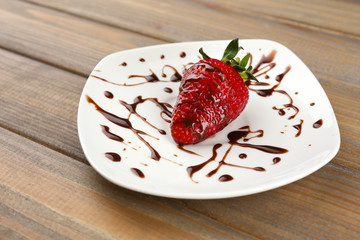 Red ripe strawberry with chocolate on wooden table