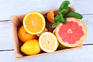 Fresh citrus fruits with green leaves in wooden box