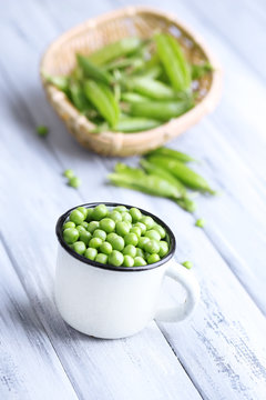 Green peas in mug on wooden background