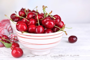 Ripe sweet cherries in bowl on wooden table
