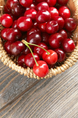 Sweet cherries in wicker basket on wooden table