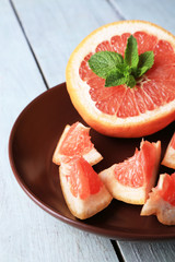 Fototapeta na wymiar Ripe grapefruits on plate on color wooden background