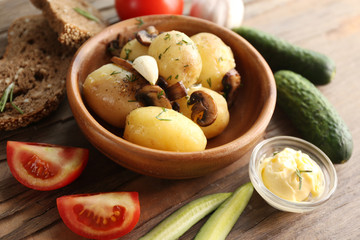 Young boiled potatoes in bowl on wooden table, close up