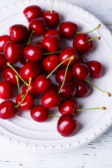 Naklejka na ściany i meble Sweet cherries on plate on wooden background