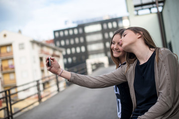 Fototapeta premium Two young girls smiling using smart phone