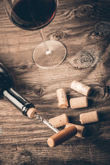 Bottle of wine with corkscrew on wooden background
