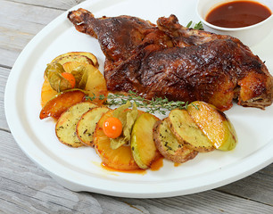 The baked half of duck with a potato, apples and pineapple