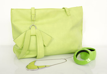 Big neon green bag with matching accessories on white shelf.