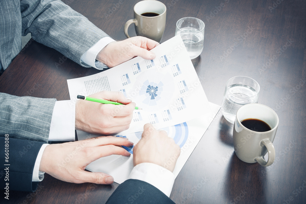 Wall mural Hands Pointing Charts at Work Desk