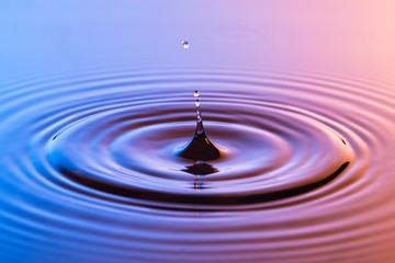 Water drop close up with concentric ripples colourful blue and a