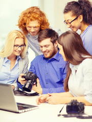 smiling team with laptop and photocamera in office