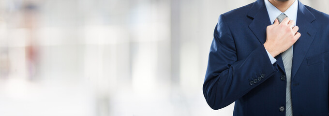 Businessman adjusting his tie over a bright background