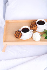 Cups of coffee on comfortable soft bed with pillows