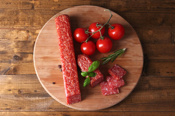 Tasty salami sausage and spices on wooden background
