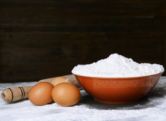 Flour in bowl on table on wooden background