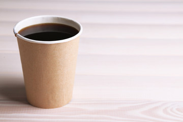 Paper cup of coffee on wooden table