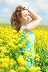Obraz na płótnie Canvas Beautiful young woman in flower field