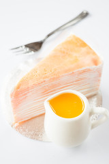 Orange whipped cream crepe cake on white background