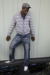 Black male model wearing derby hat looking down at water