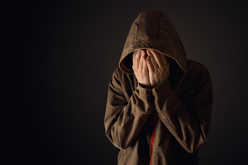 Depressive man in hooded jacket is crying