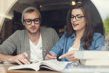 Hipster young couple studying together at cafe