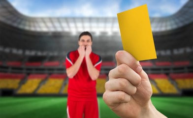 Composite image of hand holding up yellow card