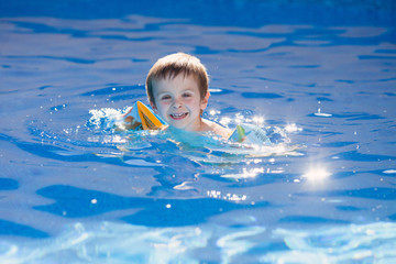 Fototapeta na wymiar Cute kid in a big swimming pool