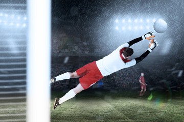 Composite image of goalkeeper in white jumping up