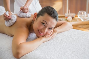 Obraz na płótnie Canvas Content brunette enjoying a herbal compress massage