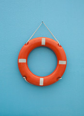 Red life buoy on blue wall. Insurance and support concept.