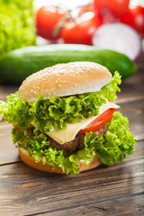 Cheeseburger with lettuce, onions and tomato in a sesame bun