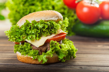 Cheeseburger with lettuce, onions and tomato in a sesame bun