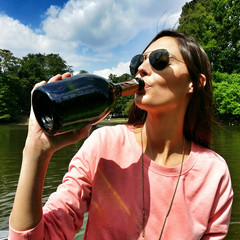 Beautiful woman drinking champagne from the bottle on a boat