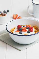 Healthy breakfast with cereals and berries in an enamel bowl