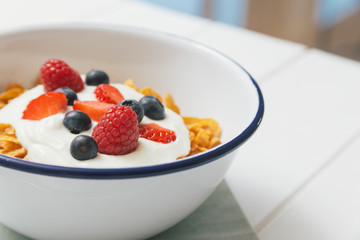 Healthy breakfast with cereals and berries in an enamel bowl