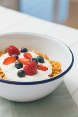 Healthy breakfast with cereals and berries in an enamel bowl