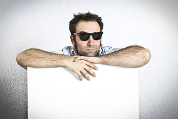 Happy man with sunglasses holding an empty white board