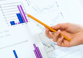 female hand pointing pencil on financial charts