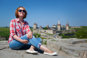 Woman siting in front castle in Kamenets-Podolsky, Ukraine