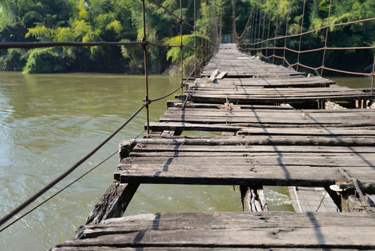 Fototapeta very old hanging footbridge across river.