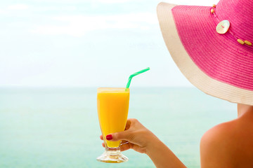 Young female, drinking orange juice, on the beach.