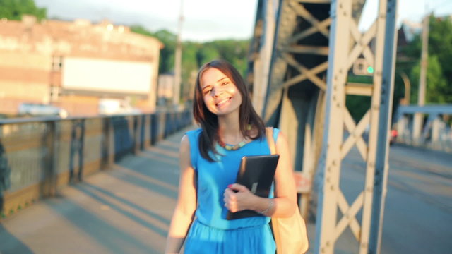 Cheerful attractive woman walking on the bridge in the city
