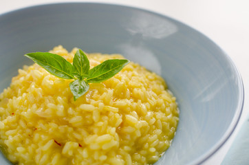 Risotto with saffron on a blue plate, white background