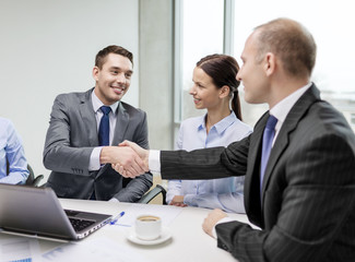 two businessman shaking hands in office