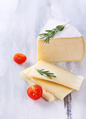 Tasty Camembert cheese with tomato and rosemary, on wooden